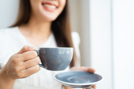 Asian businesswoman holding a coffee cup on hand during relaxing in the coffee shop. Asian smart and good looking businesswoman taking a break in coffee shop.の写真素材