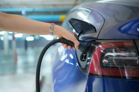 Beautiful Asian woman connecting a AC Type 2 EV charging connector to a vehicle, woman preparing an EV - electric vehicle charging connector for recharge a vehicle.の写真素材