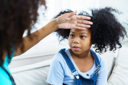 African American ethnicity female doctor and little girl in hospital, pediatrician taking to a little girl who laying down on the bed or sofa in hospital to talk about her sickness.の写真素材
