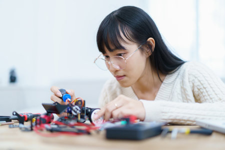 Happy cheerful Asian ethnicity female university student learning about robotic and programing by herself, woman assemble a robot and coding.の写真素材