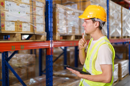 Senior warehouse supervisor inspecting or checking an items inventory in the warehouse. Male logistic warehouse worker checking a cartons on shelf.の写真素材