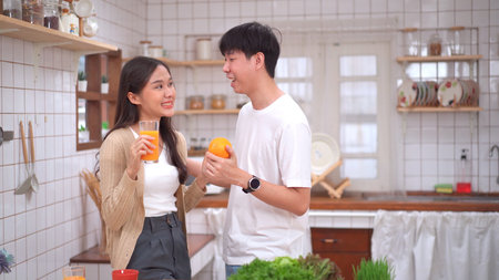 Happy cheerful Asian man and woman showing a half round of a fresh orange fruit to camera together and smiling.の写真素材