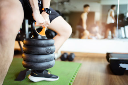 Happy cheerful Asian sportsman doing a weight training exercise in squats weight lifting. Asian sporty man doing a squat weight lifting workout in an indoor fitness gym.の写真素材
