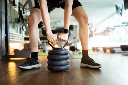 Happy cheerful Asian sportsman doing a weight training exercise in squats weight lifting. Asian sporty man doing a squat weight lifting workout in an indoor fitness gym.の写真素材