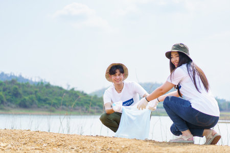 Group of Asian young people volunteer helping to collecting or picking up a plastic bottle garbage on the ground in park. Sustainability and environment conservation concept.の写真素材