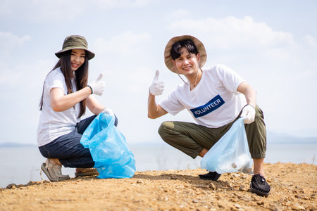 Group of Asian young people volunteer helping to collecting or picking up a plastic bottle garbage on the ground in park. Sustainability and environment conservation concept.の写真素材