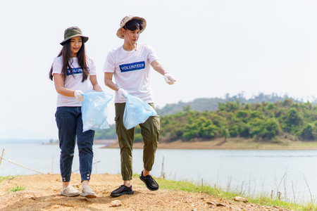 Group of Asian young people volunteer helping to collecting or picking up a plastic bottle garbage on the ground in park. Sustainability and environment conservation concept.の写真素材