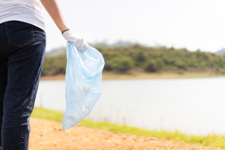 Group of Asian young people volunteer helping to collecting or picking up a plastic bottle garbage on the ground in park. Sustainability and environment conservation concept.の写真素材