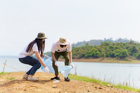 Group of Asian young people volunteer helping to collecting or picking up a plastic bottle garbage on the ground in park. Sustainability and environment conservation concept.の写真素材