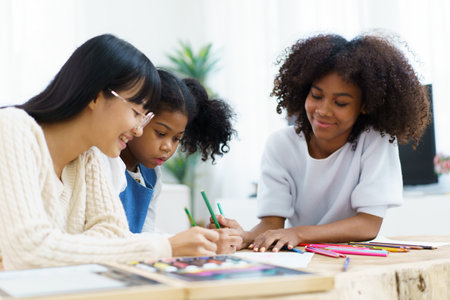 Happy cheerful American - African ethnicity little girl enjoy practice drawing and painting together with her sisters. Diversity in family and people concept.の写真素材