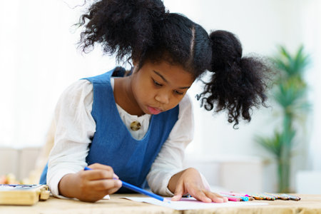 Happy cheerful little American - African ethnicity girl enjoy practice drawing and painting on paper, little girl learning art and creativity skill.の写真素材