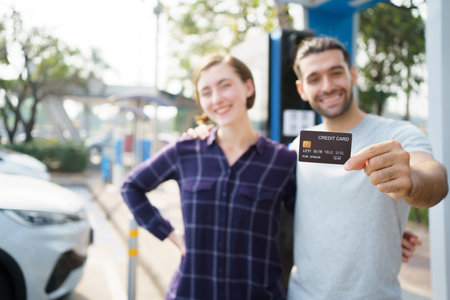 Lovely young caucasian couple charging their electric vehicle or EV car at fast charging EV station. Cashless or online payment for electric vehicle charging station. Sustainable energy concept.の写真素材