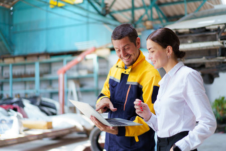 Caucasian white young woman taking her car to garage to have an annual check up and talking or discussing to technician. Automobile repairing and diagnostics service business concept.の写真素材