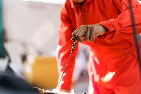 Senior Asian man checking or measuring a vehicle oil engine or engine lubricant level by using oil stick indicator. Senior professional repairman inspecting an oil engine in an old car.の写真素材