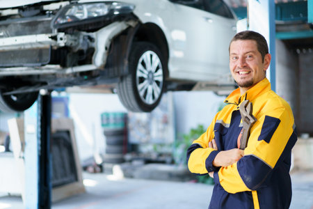 Professional caucasian white automobile technician holding a wrench and making crossed arms and looking at camera.の写真素材