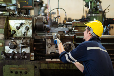 Professional caucasian white ethnicity male technician operating the heavy duty machine in the lathing factory. Technician in safety and helmet suit controlling a machine in factory.の写真素材