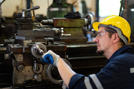 Professional caucasian white ethnicity male technician operating the heavy duty machine in the lathing factory. Technician in safety and helmet suit controlling a machine in factory.の写真素材