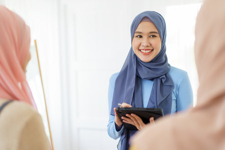 Group of a beautiful smart Asian muslim woman standing in the room and having a discussion together. Modern muslim society concept, women muslim student talking.の写真素材