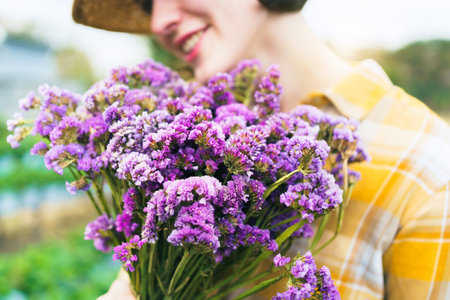 Beautiful caucasian white ethnicity young woman holding a beautiful blossom bouquet of flower on hand and showing to camera close up. Woman holding a flower bouquet colorized in vintage tone.の写真素材