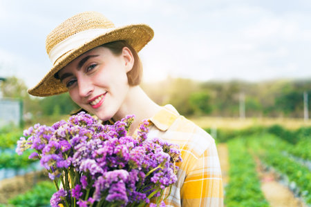Beautiful caucasian white ethnicity young woman holding a beautiful blossom bouquet of flower on hand and showing to camera close up. Woman holding a flower bouquet colorized in vintage tone.の写真素材