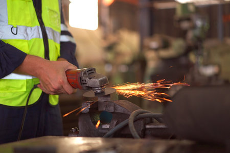 Heavy industry metal work worker using metal grinder machine sharpening a metal pipe close up.の写真素材
