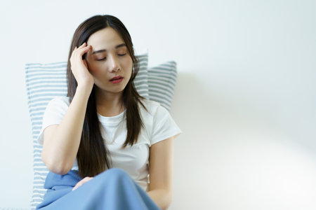 Unhappy - unwell Asian young woman having a mental health problem, woman feels uncomfortable after woke up from the bed. Young woman got a depression problem and mental burnout.の写真素材