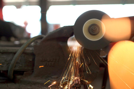 Heavy industry metal work worker using metal grinder machine sharpening a metal pipe close up.の写真素材
