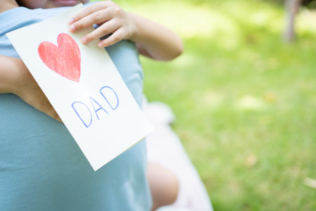 Lovely Asian little young boy giving his daddy the greeting card for the international father's day, lovely boy gives his father a drawing DIY Father's Day greeting card.の写真素材
