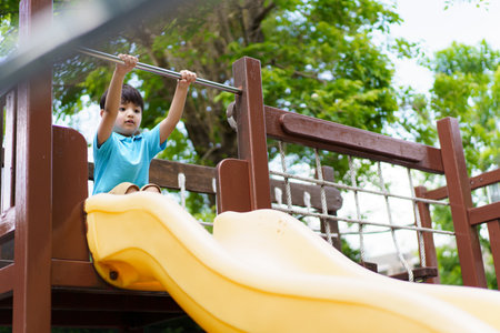 Lovely Asian little boy enjoy playing and exercising in the playground, boy enjoy playing a slider.の写真素材