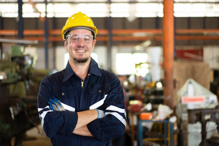 Professional caucasian white ethnicity male technician operating the heavy duty machine in the lathing factory. Technician in safety and helmet suit controlling a machine in factory.の写真素材