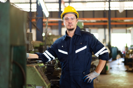 Professional caucasian white ethnicity male technician operating the heavy duty machine in the lathing factory. Technician in safety and helmet suit controlling a machine in factory.の写真素材