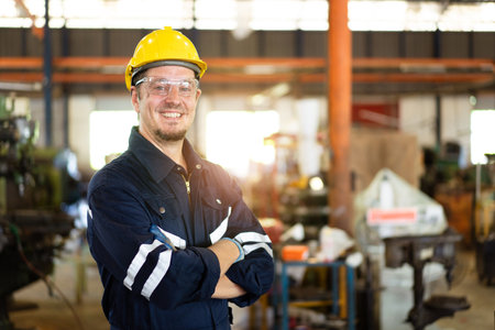 Professional caucasian white ethnicity male technician operating the heavy duty machine in the lathing factory. Technician in safety and helmet suit controlling a machine in factory.の写真素材
