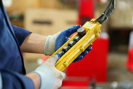 Factory worker - technician controlling a heavy crane in factory close up at his hands holing a crane controller.の写真素材