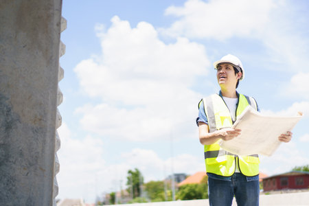 Asian professional - senior cilvil or construction engineer inspecting a segmenting bridge blueprint...