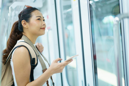 Happy Asian female tourist traveling in across the country by railway transportation system. Woman holding on the handle grip while traveling in the train.の写真素材