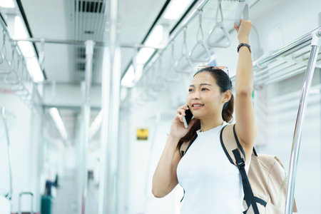 Happy Asian female tourist traveling in across the country by railway transportation system. Woman holding on the handle grip while traveling in the train.の写真素材