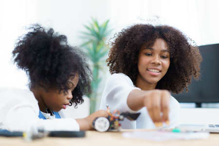 African black ethnicity sibling learn assembling robot and electronic devices. Woman teaching her sister about electronics, robot and programming.の写真素材