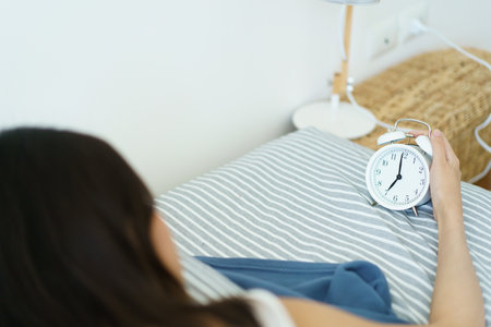 Asian young woman sleeping on the cozy bed in the early morning and trying to turn oの写真素材