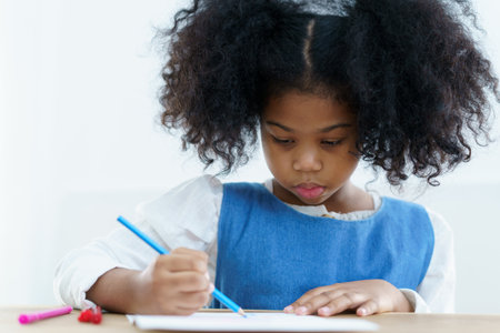 Happy cheerful little American - African ethnicity girl enjoy practice drawing and painting on paper, little girl learning art and creativity skill.の写真素材