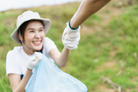Friends helps and supports each other while doing the voluntary activity, woman pulling her tired friend from the ground.の写真素材