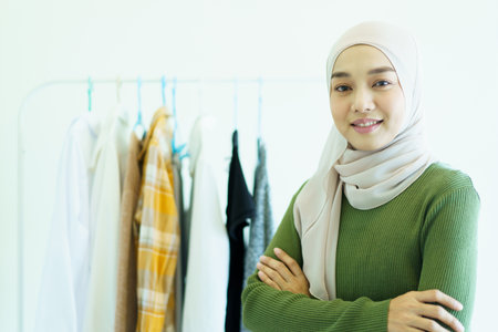 Happy cheerful Asian young muslim woman choosing a clothes in fitting room on a clothing hanger. Modern lifestyles concept of muslim people.の写真素材