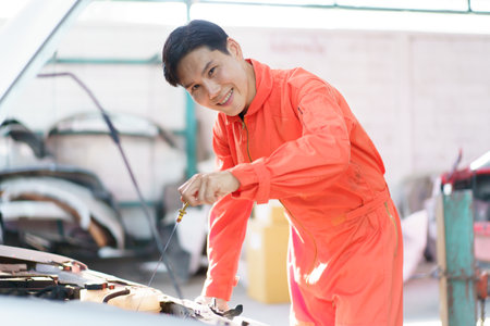 Professional automobile technician inspects customer's vehicle liquid system and engine oil level. Technician working in garage.の写真素材