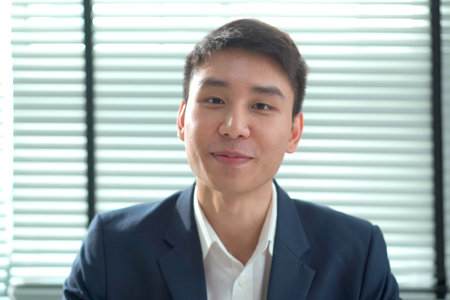 Smart - good looking senior asian businessman speaking to the camera in his office, business man talking to camera on an online video conference.の写真素材
