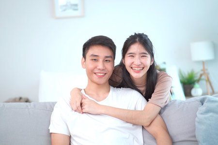 Lovely Asian young couple relaxing together in living room.の写真素材