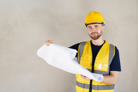 Portrait of smart and good looking caucasian white male foreman or construction contractor reviewing the building layout on blueprint close up. Construction contractor - inspecting blueprint on paper.の写真素材