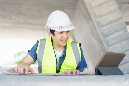 Asian professional - senior cilvil or construction engineer inspecting a segmenting bridge blueprint and construction plan at the site, civil engineer working at bridge construction site.の写真素材