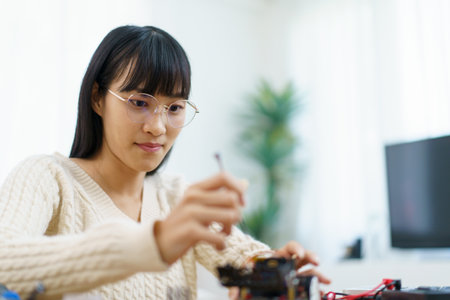 Happy cheerful Asian ethnicity female university student learning about robotic and programing by herself, woman assemble a robot and coding.の写真素材