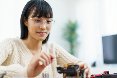 Happy cheerful Asian ethnicity female university student learning about robotic and programing by herself, woman assemble a robot and coding.の写真素材