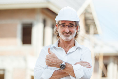 Portrait of senior civil engineer or head of engineer standing at the construction site and looking at camera. Senior foreman at construction site portrait.の写真素材