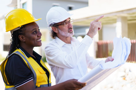 Team of engineer discuss at construction site. Female black ethnicity engineer taking to caucasian...